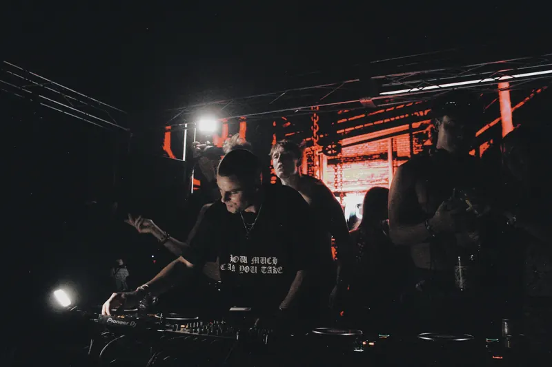 A DJ works at the decks beneath red stage visuals.