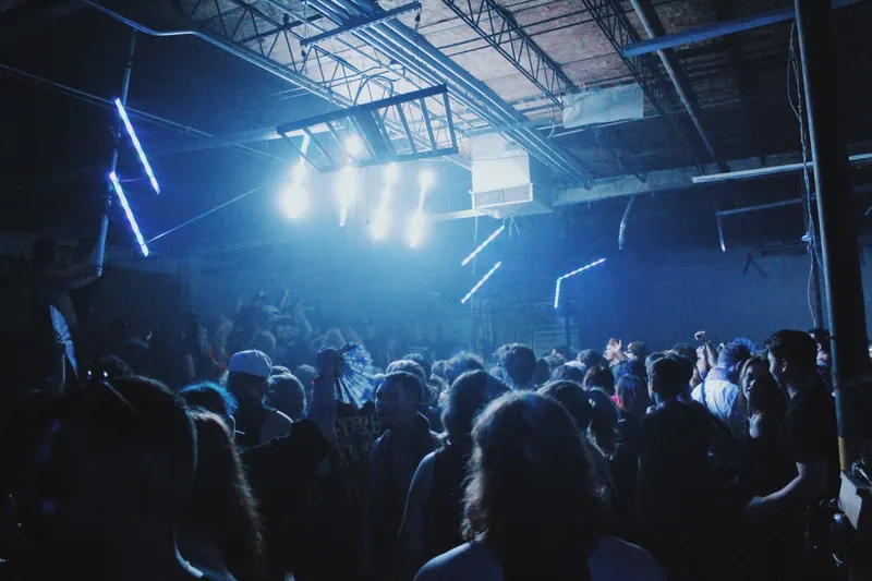Blue-white lighting over a warehouse dancefloor.