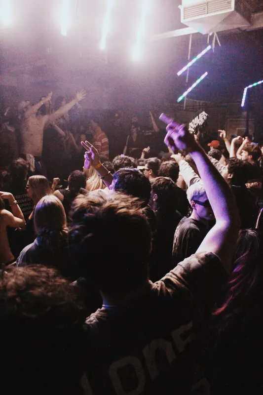A crowd faces the stage under pink and white lights.