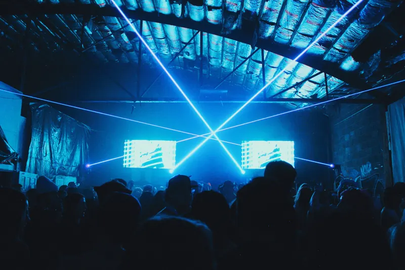 Blue lasers cross over the crowd and two stage screens.