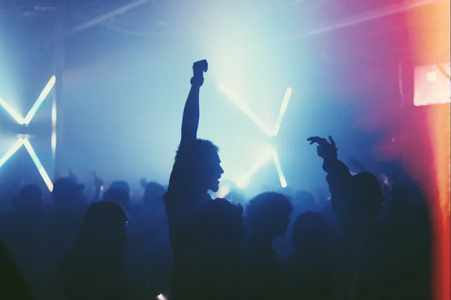 A raised hand silhouetted against blue-white stage lights.